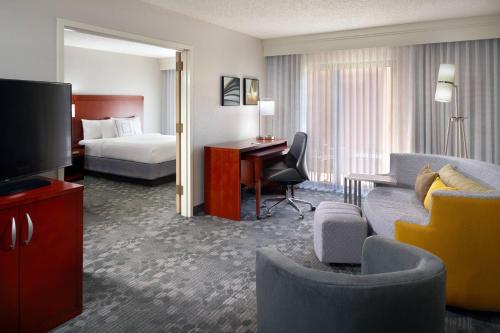 a hotel room with a bed and a living room at Courtyard by Marriott Macon in Macon