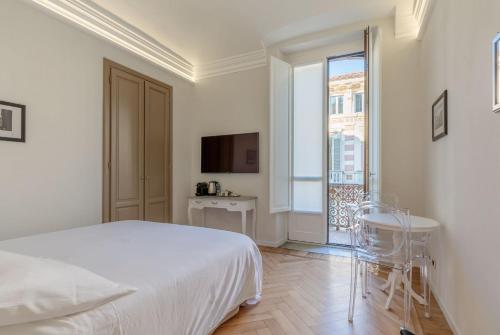 a white bedroom with a bed and a balcony at XX SETTEMBRE Urban Relais in Turin