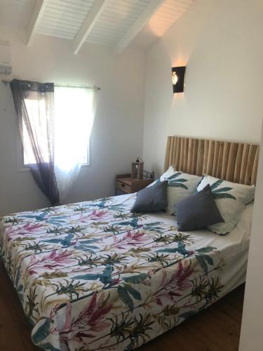 Un dormitorio con una cama con un edredón colorido y una ventana en Maison PAPAGAYO, en Oyster Pond