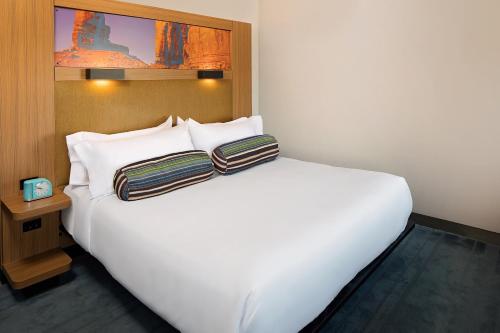 a white bed with two pillows on top of it at Aloft Tucson University in Tucson
