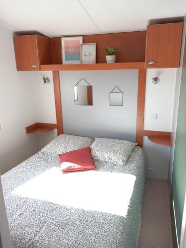 Dormitorio pequeño con cama con almohada roja en Bungalow, en Sainte-Marie-du-Mont