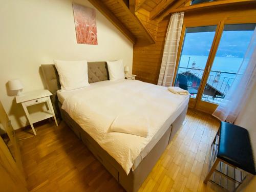een slaapkamer met een groot bed en een groot raam bij Lake View Residence -16 in Niederried