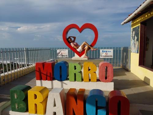 a woman sitting on top of a sign with a heart at Pousada Familiar Beberibe in Beberibe