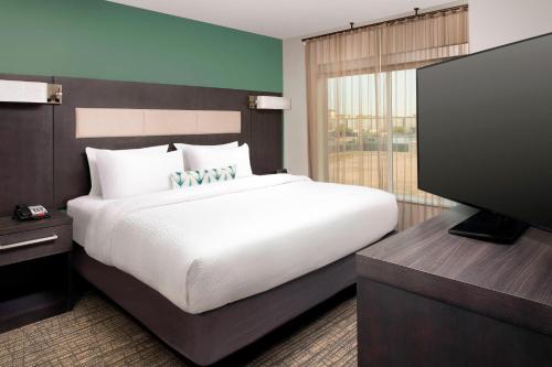 Residence Inn by Marriott New Orleans Elmwood في Elmwood: غرفة نوم بسرير كبير وتلفزيون بشاشة مسطحة