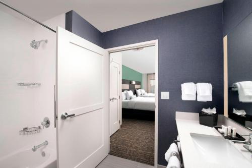 a bathroom with a sink and a shower and a bed at Residence Inn by Marriott New Orleans Elmwood in Elmwood