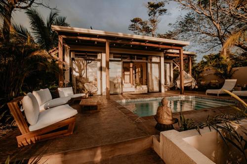 une villa avec une piscine, des chaises et une maison dans l'établissement Sansara Surf Yoga & Resort, à Cambutal