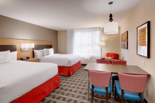 a hotel room with two beds and a table and chairs at TownePlace Suites by Marriott Salt Lake City Draper in Draper