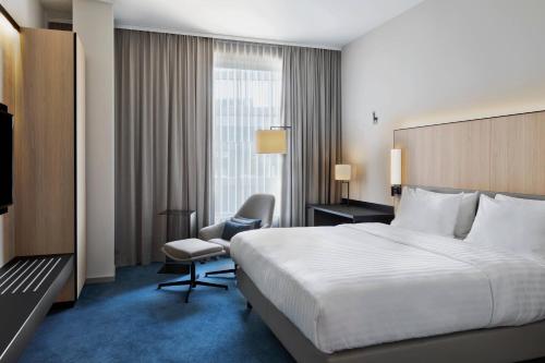 a hotel room with a large bed and a chair at Courtyard by Marriott Freiburg in Freiburg im Breisgau