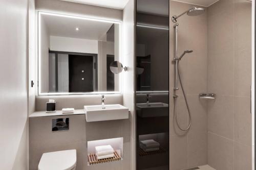 La salle de bains est pourvue d'une douche, de toilettes et d'un lavabo. dans l'établissement Courtyard by Marriott Freiburg, à Fribourg-en-Brisgau