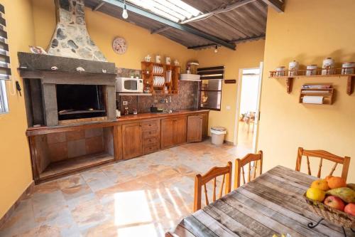 a large kitchen with a table and a fireplace at Casa el Monte in San Juan del Reparo