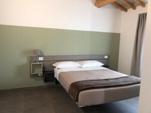 1 dormitorio con 1 cama y TV en la pared en B&B Il Passo, en Urbino