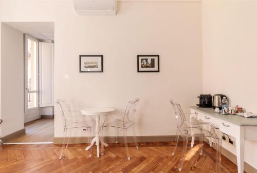 a kitchen with white chairs and a table at XX SETTEMBRE Urban Relais in Turin