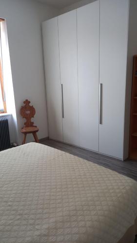 Schlafzimmer mit weißen Schränken und einem Bett in der Unterkunft Delizioso bilocale a Trento in Trient