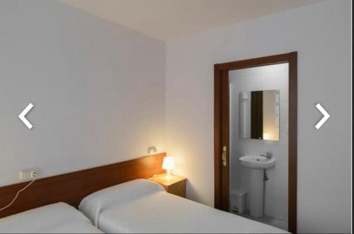 a bedroom with two beds and a sink and a mirror at Casa Anglicana del Peregrino/ Pensión Santa Cristina in Santiago de Compostela