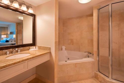 a bathroom with a tub and a sink and a mirror at Courtyard by Marriott Key Largo in Key Largo
