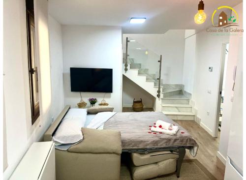 sypialnia z łóżkiem i telewizorem oraz schody w obiekcie Casa de la GALERA w mieście Toledo