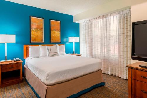 Residence Inn Tampa Westshore Airport في تامبا: غرفة نوم بسرير كبير وتلفزيون بشاشة مسطحة