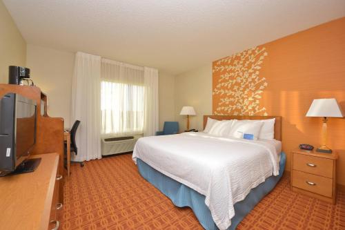 a hotel room with a bed and a flat screen tv at Fairfield Inn and Suites by Marriott Williamsport in Williamsport