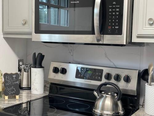 a microwave above a stove with a tea kettle at Look No Further! in Nashville
