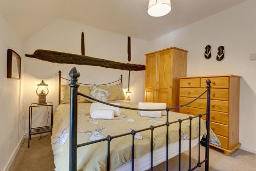 a bedroom with a bed and a dresser at Lavender Cottage in Stiffkey