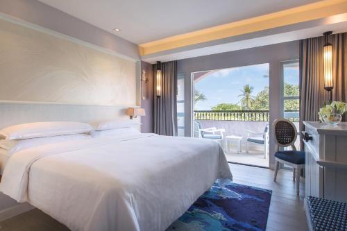 een slaapkamer met een groot wit bed en een balkon bij Sheraton Samui Resort in Chaweng Noi Beach