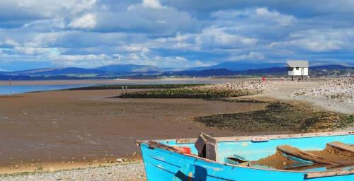 a blue boat sitting on the shore of a beach at Basement Studio by the Bay in Morecambe