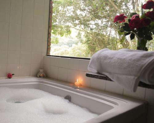 a bath tub with a candle and a window at Hotel Ponto de Luz in Joanópolis