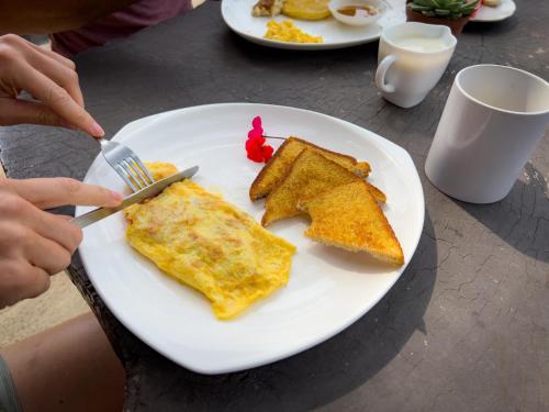 a person eating a plate of food with eggs and toast at Casa Tranquilo Hostel in Monteverde Costa Rica