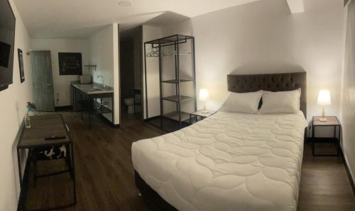 a bedroom with a large white bed and two lamps at HOTEL GALLERY URBAN in Bogotá