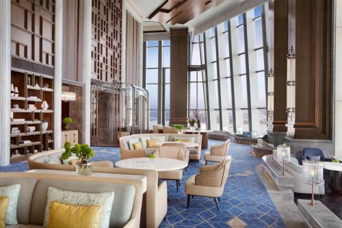 un vestíbulo con sofás, mesas y ventanas en The Ritz-Carlton, Harbin en Harbin