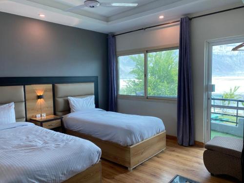 a bedroom with two beds and a window at Eat and Read Hotel in Skardu