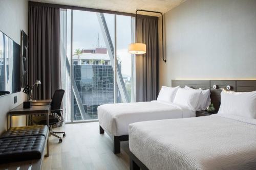 een hotelkamer met 2 bedden en een groot raam bij AC Hotel by Marriott Guadalajara Mexico in Guadalajara