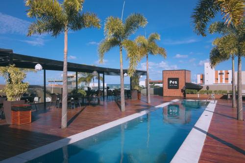 uma piscina com palmeiras e um edifício em LS Hotel em João Pessoa