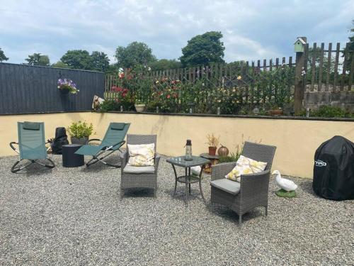 a patio with chairs and a table and a fence at Rural cosy retreat for two near Port Isaac in Delabole