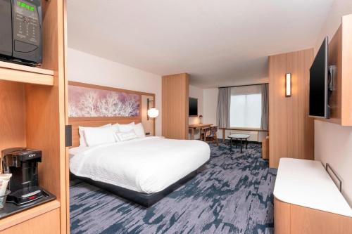 a hotel room with a bed and a flat screen tv at Fairfield Inn & Suites by Marriott Fair Oaks Farms in Fair Oaks