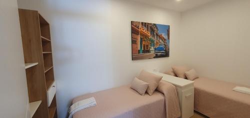 ein kleines Schlafzimmer mit einem Bett und einem Gemälde an der Wand in der Unterkunft Pisos uso turistico Torno-Cubelas-Caosa Buenavista in San Cibrao