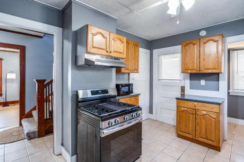 a kitchen with a stove and wooden cabinets at Spacious Home with In-Unit Laundry, Parking, 1GB WiFi, & Patio Deck in Rochester
