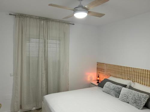 FUENGIROLA Castillo Malaga PARADAISE 3 في فوينخيرولا: غرفة نوم بسرير أبيض ومروحة سقف