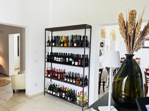 une étagère remplie de bouteilles de vin à côté d'un vase dans l'établissement Mirodìa, à Sternatia