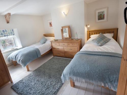 a bedroom with two beds and a wooden dresser at Ford Hill Cottage in East Down