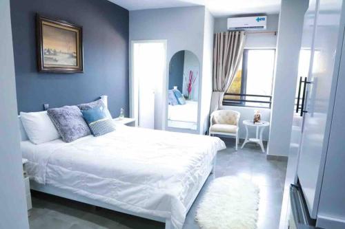 een blauwe slaapkamer met een wit bed en een stoel bij Sylz Residence Studio 1- 5 Mins from Labadi & Laboma Beaches in Accra