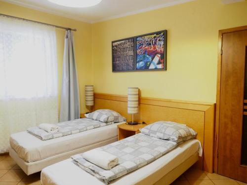 a bedroom with two beds and a window and a lamp at Zajazd u Basi in Otyń