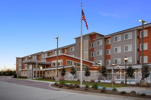 an apartment building with an american flag on a pole at Residence Inn by Marriott Shreveport-Bossier City/Downtown in Bossier City