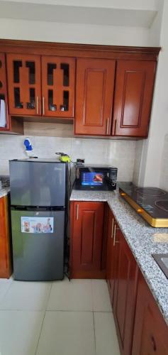 La cuisine est équipée d'armoires en bois et d'un réfrigérateur en acier inoxydable. dans l'établissement Cozy 3bedrooms Apartment, à Addis-Abeba