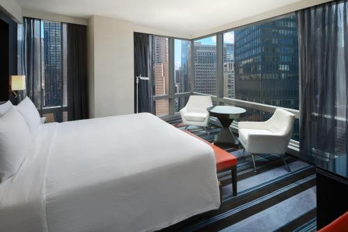um quarto com uma cama e uma varanda com uma mesa e cadeiras em Courtyard by Marriott New York Manhattan/Central Park em Nova Iorque
