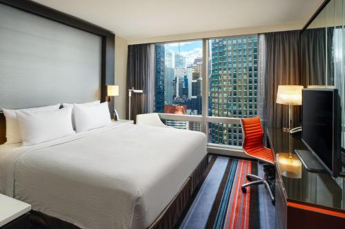 ニューヨークにあるコートヤード バイ マリオット ニューヨーク マンハッタン セントラルパークのベッドと大きな窓が備わるホテルルームです。