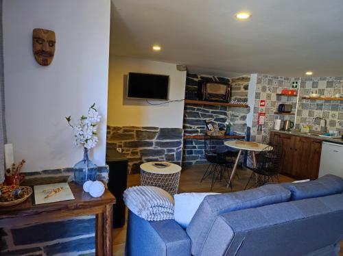 a living room with a blue couch and a kitchen at Recanto da Encosta T0 in Bragança
