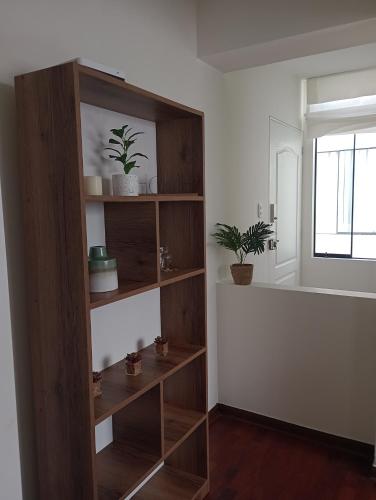 een houten boekenplank in een kamer met potplanten bij Romina's Home in Lima