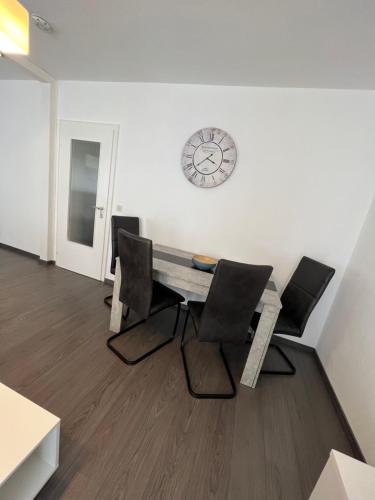 ein Zimmer mit Stühlen, einem Tisch und einer Uhr an der Wand in der Unterkunft Nik Apartment in Oberhausen