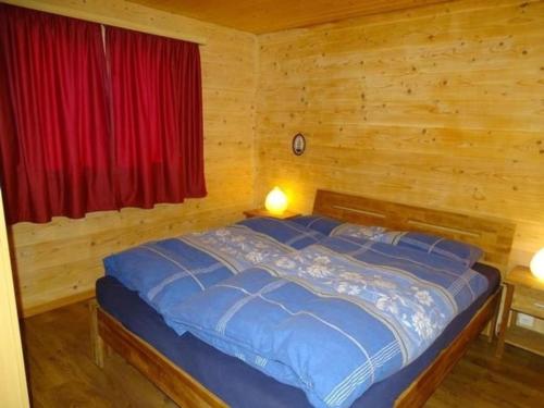 a bed in a wooden room with a red window at Chalet Stefanino, 3 12 Zimmer in Bellwald